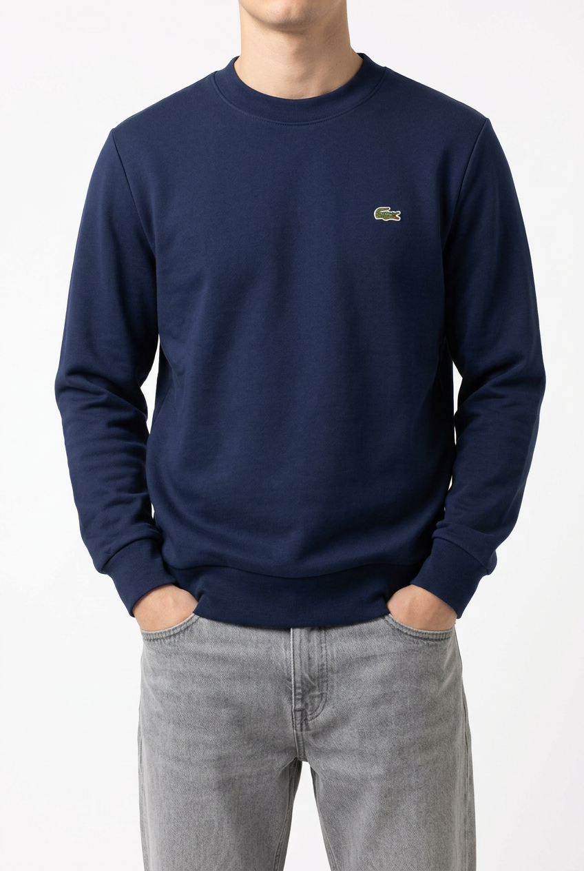 Felpa Lacoste blu indossata con jeans grigio chiaro, mani in tasca e viso escluso